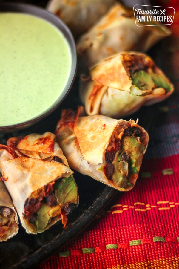 Healthy Baked Fiesta Avocado Egg Rolls on a plate with a dipping sauce on the side.