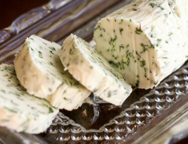 Slices of herbed butter on a glass butter dish