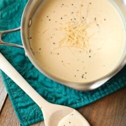 Homemade Alfredo Sauce in a pan with a serving spoon