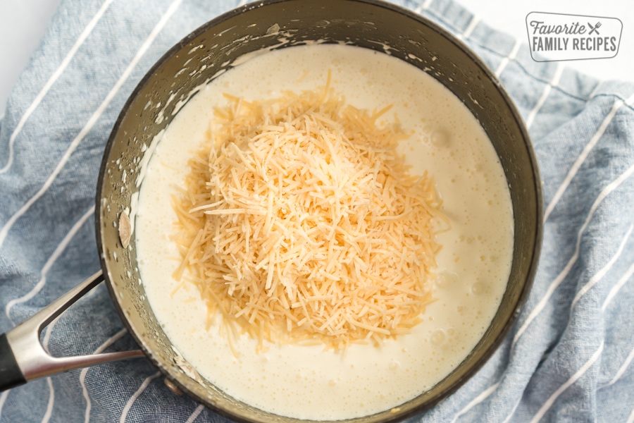 A pile of Parmesan cheese on top of sauce in a pot