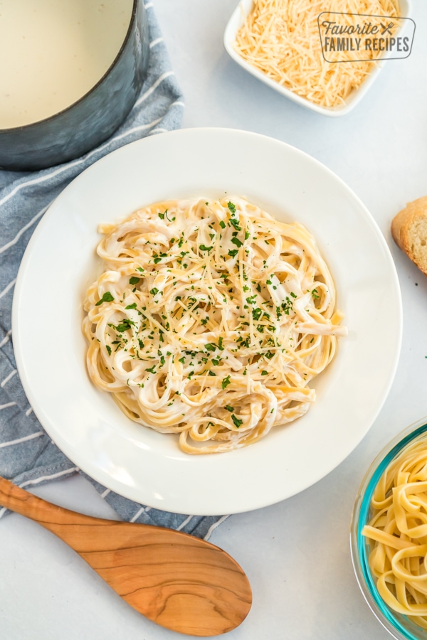 A large bowl of pasta with Alfredo sauce, parmesan and parsley