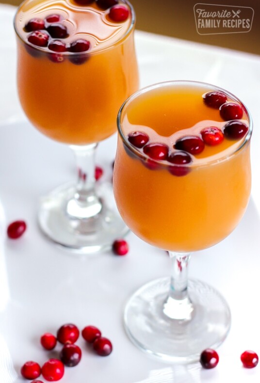 Two stemmed glasses filled with Homemade Sparkling Cider topped with fresh cranberries