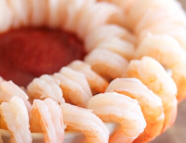 A double cocktail shrimp ring with cocktail sauce in the center
