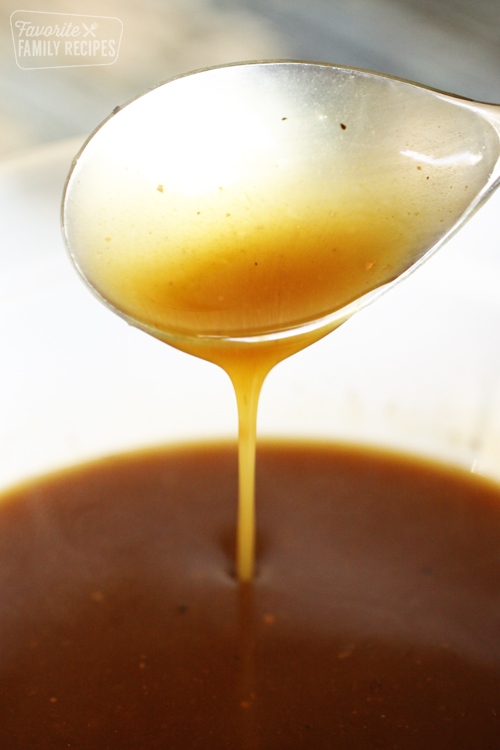 Beef gravy dripping from a spoon into a bowl of gravy