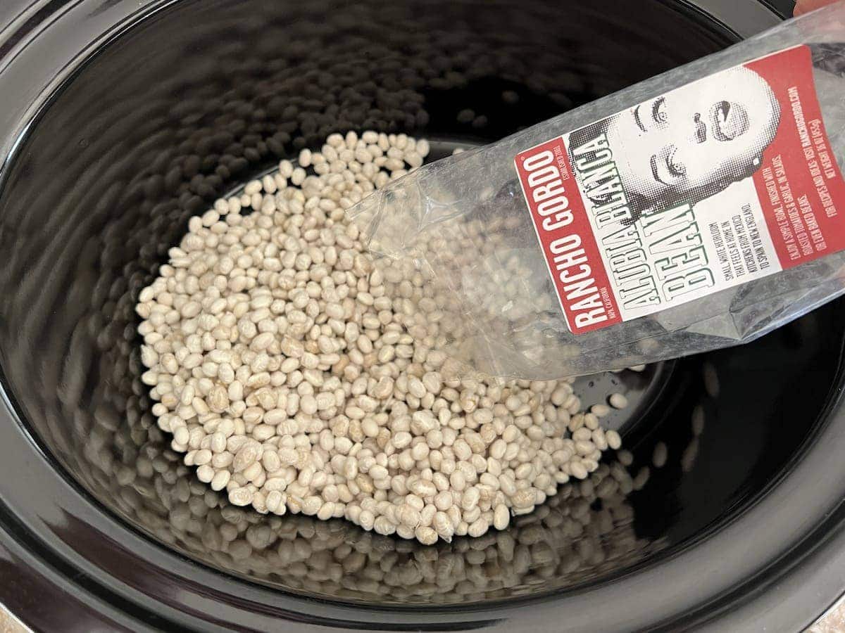 Dry white beans being poured into a Crock Pot