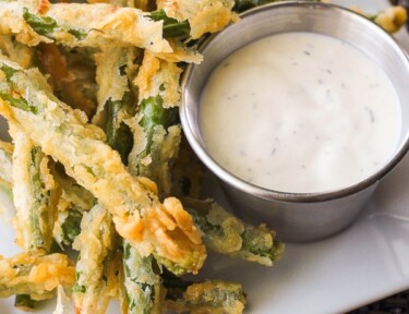 Lightly Fried Green Beans with a side of Lemon Dill Dip on a white plate.