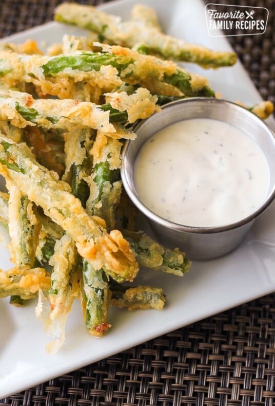 Lightly Fried Green Beans with a side of Lemon Dill Dip on a white plate.