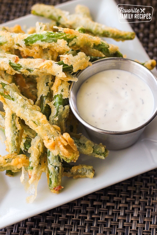 Lightly Fried Green Beans with a side of Lemon Dill Dip on a white plate.