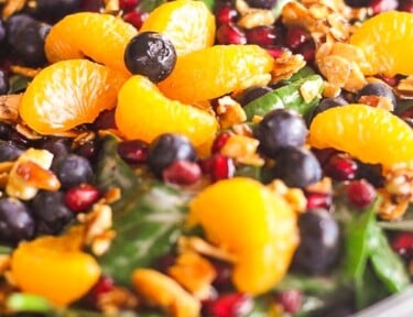 Mandarin Spinach Salad with Candied Pecans, blueberries, and pomegranite seeds in a big glass bowl.