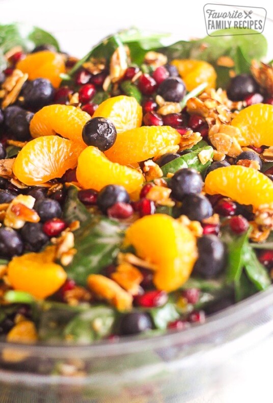 Mandarin Spinach Salad with Candied Pecans, blueberries, and pomegranite seeds in a big glass bowl.