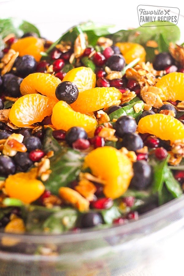 Mandarin Spinach Salad with Candied Pecans, blueberries, and pomegranite seeds in a big glass bowl.