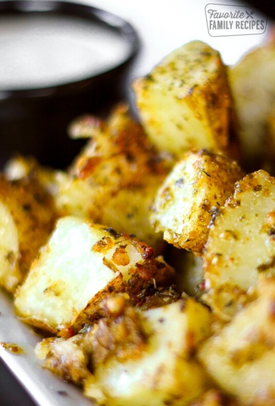Close up of Pesto Potatoes with a side of ranch in the background.