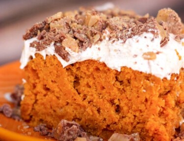 pumpkin poke cake on an orange plate with crumbles on the side