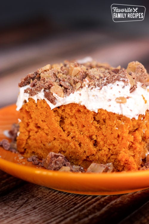 Pumpkin poke cake on an orange plate with crumbles on the side.