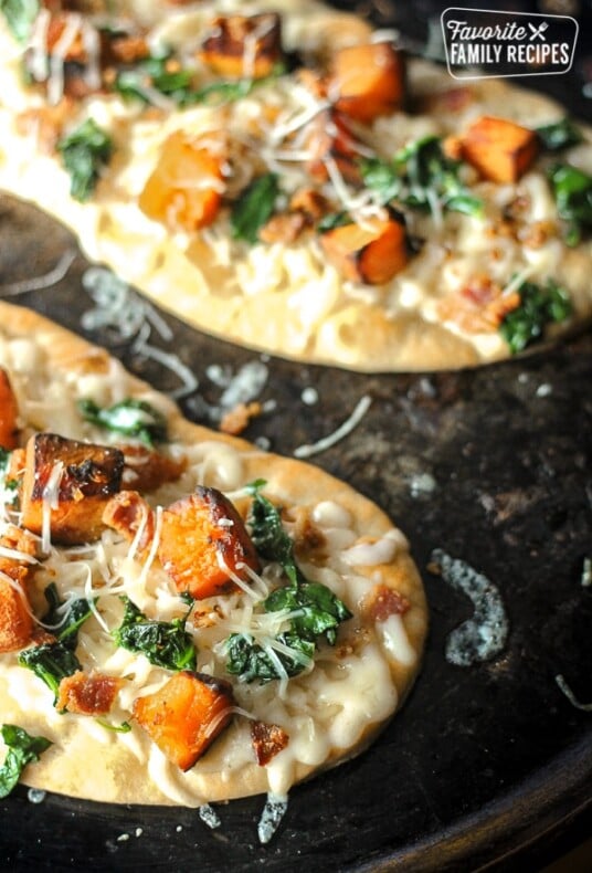 Roasted butternut squash pizza on a black plate.