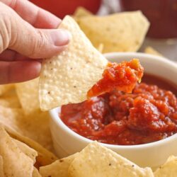 Canned Salsa in a bowl with a chip being dipped into it.