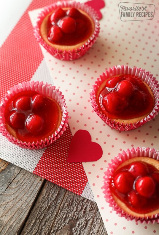 4 Mini Cherry Cheesecakes in pink and red paper liners.