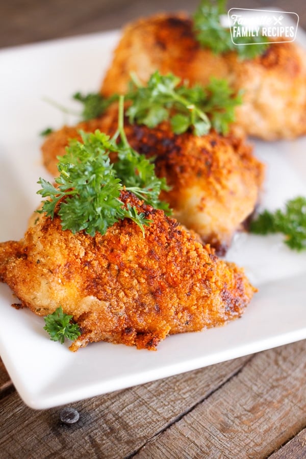 3 pieces of Paprika & Parmesan Chicken topped with a garnish on a white plate