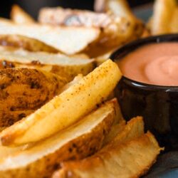 Baked Potato Wedges on a plate with fry sauce in a little black bowl.
