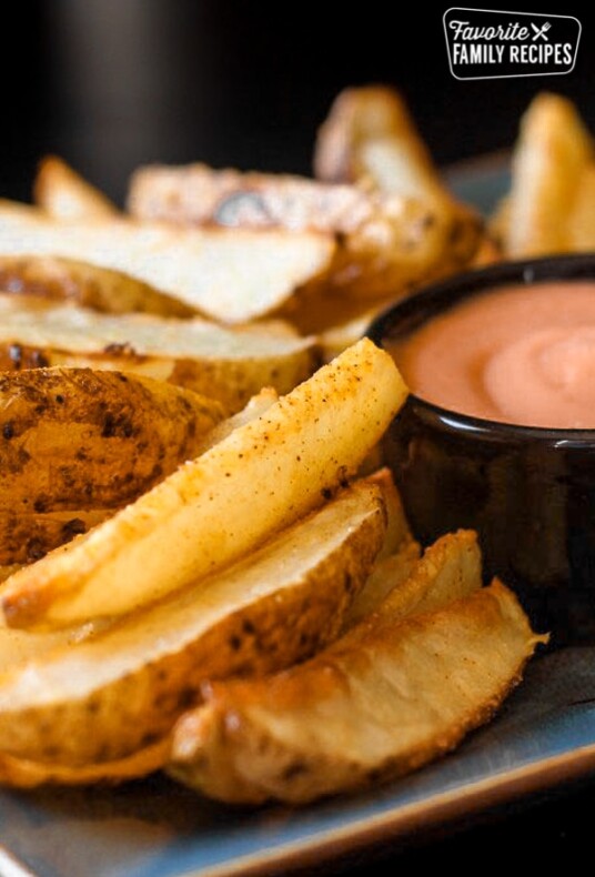 Baked Potato Wedges on a plate with fry sauce in a little black bowl.