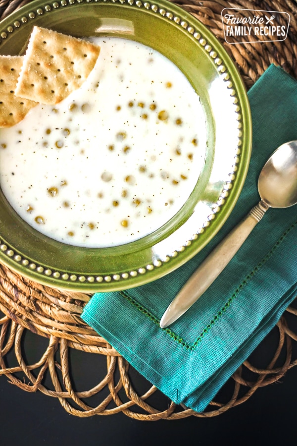 Basil and Sweet Pea Soup with 2 saltine crackers in a green bowl.