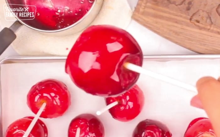 The side of a candy apple with a white stick on top.