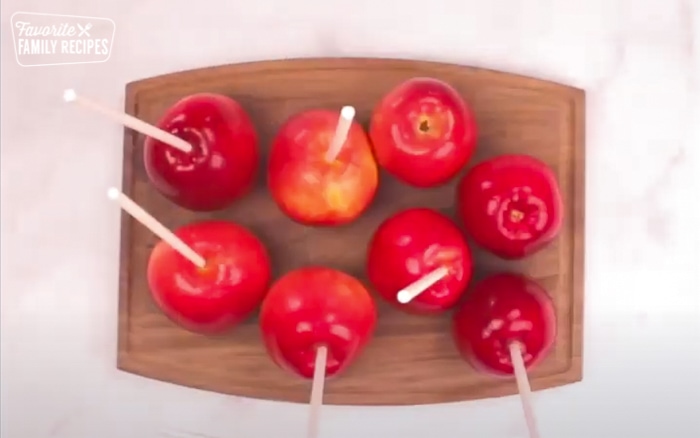 Candy apples on a wooden cutting board.