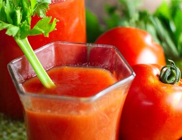 Canned Homemade Tomato Juice in a glass with a piece of celery sticking out.
