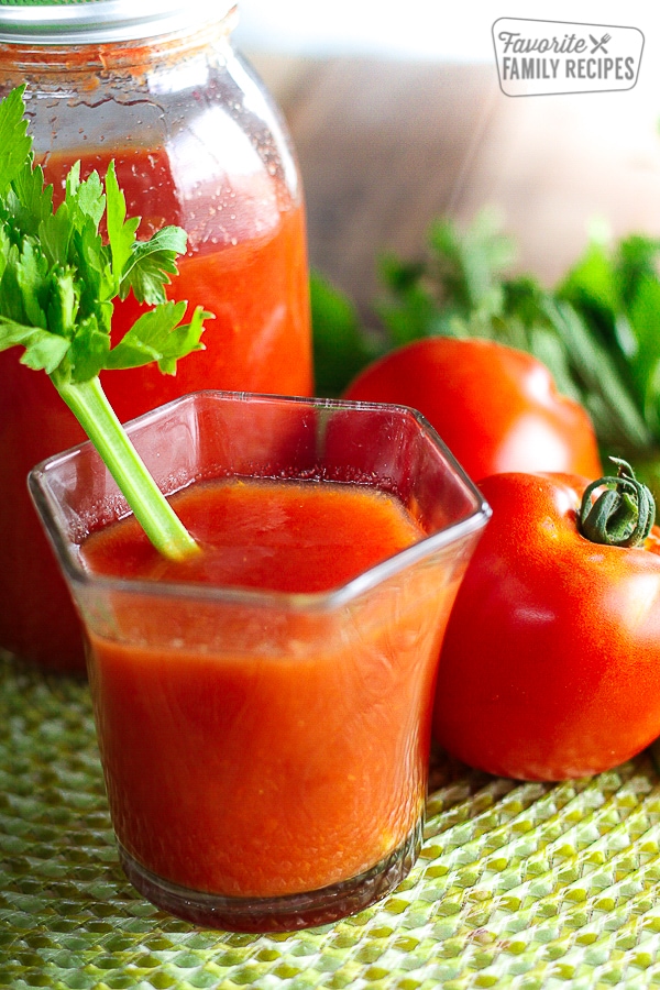 Canned Homemade Tomato Juice in a glass with a piece of celery sticking out.