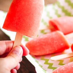 Caribbean Passion Popsicles, one is being held and the other popsicles are on a tray in the background.