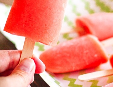 Caribbean Passion Popsicles, one is being held and the other popsicles are on a tray in the background.