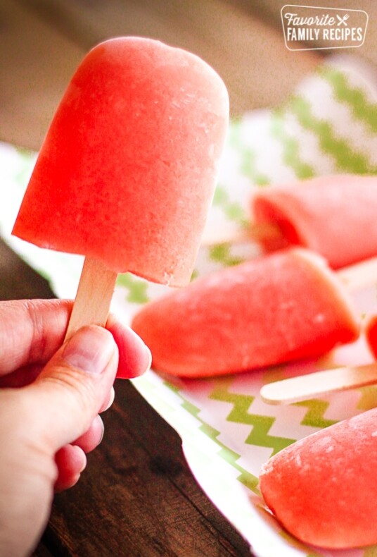 Caribbean Passion Popsicles, one is being held and the other popsicles are on a tray in the background.