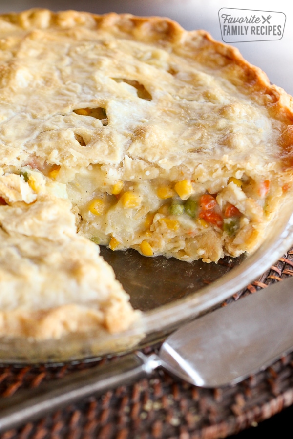 A chicken pot pie with vegetables in a pie plate with a slice cut out 