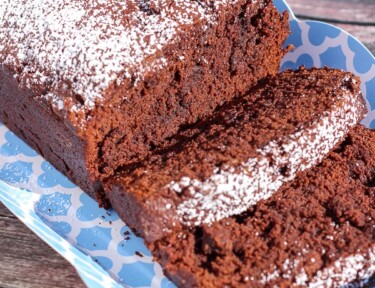Sliced Chocolate Banana Bread sprinkled in powdered sugar on a blue tray.