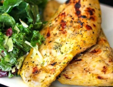 Two pieces of Coconut Curry Grilled Chicken with a salad on the side.