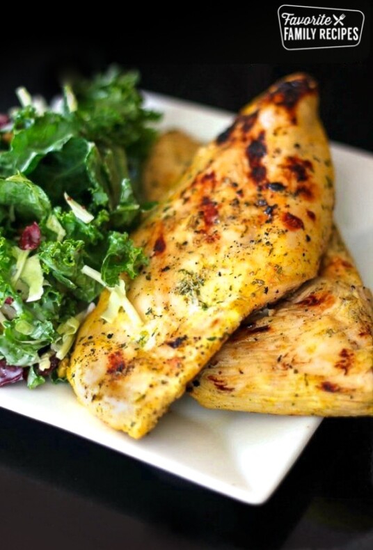 Two pieces of Coconut Curry Grilled Chicken with a salad on the side.