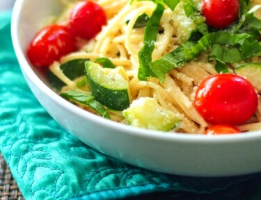 Creamy Basil Noodles topped with vegetables in a white bowl.