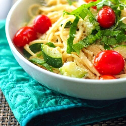 Creamy Basil Noodles topped with vegetables in a white bowl.