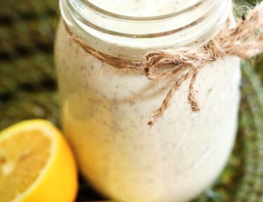 Creamy Basil Dressing in a mason jar with lemons on the side.