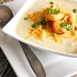 Creamy Broccoli Cauliflower Soup topped with cheese and croutons in a white bowl.