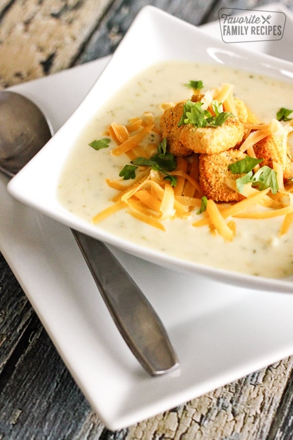 Creamy Broccoli Cauliflower Soup topped with cheese and croutons in a white bowl.