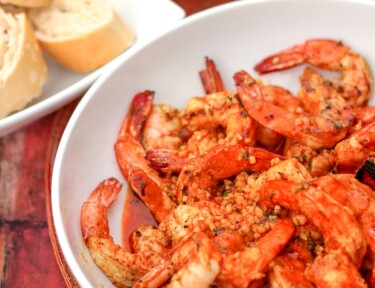 Creole Butter Shrimp in a white bowl with bread on the side.