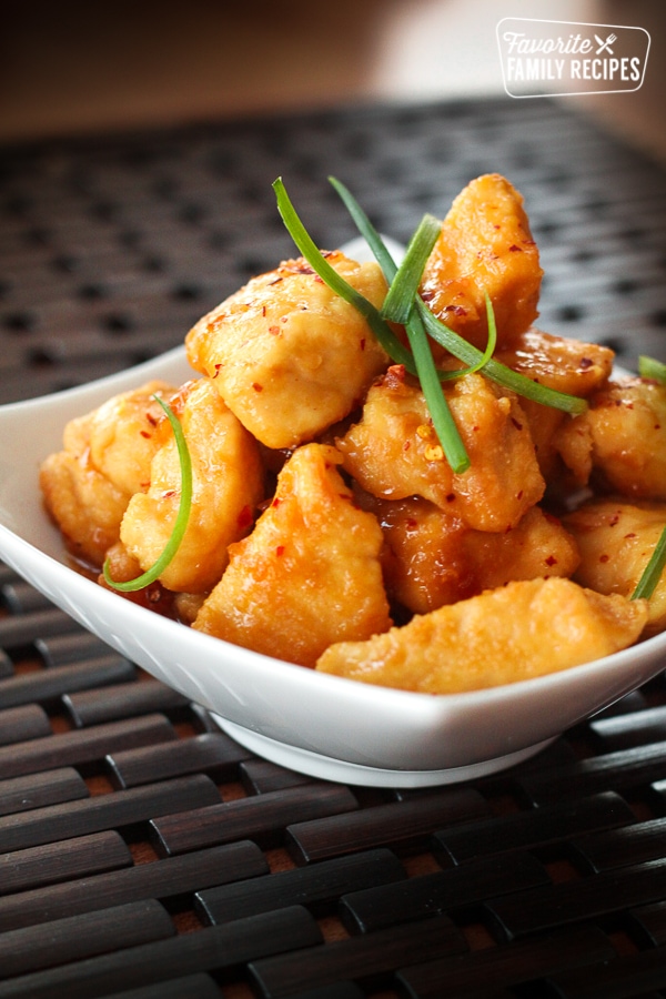 Crock Pot General Tso Chicken in a white bowl garnished with green onion