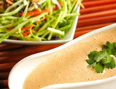 Easy Creamy Thai Peanut Dressing in a gravy boat with a salad in the background.