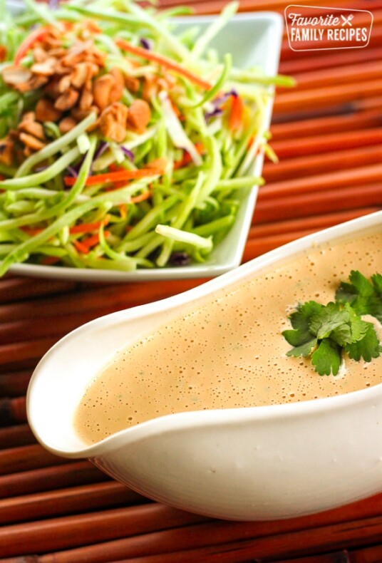 Easy Creamy Thai Peanut Dressing in a gravy boat with a salad in the background.