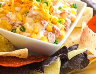 Creamy Corn dip in a square white bowl with tortilla chips on the side