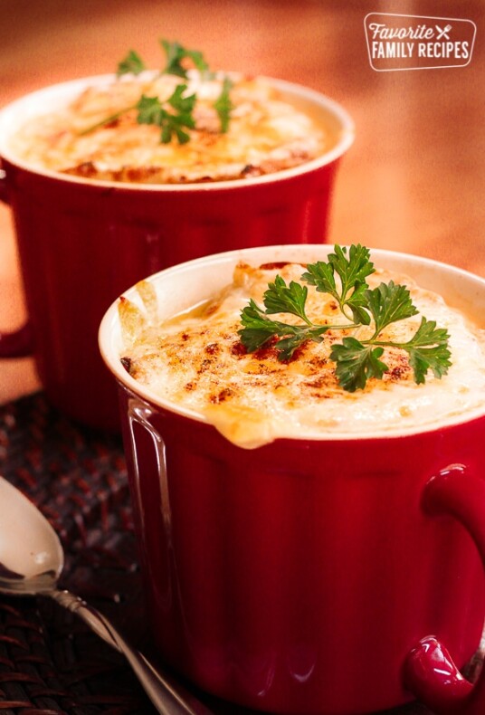 French Onion Soup in a red mug topped with a garnish.