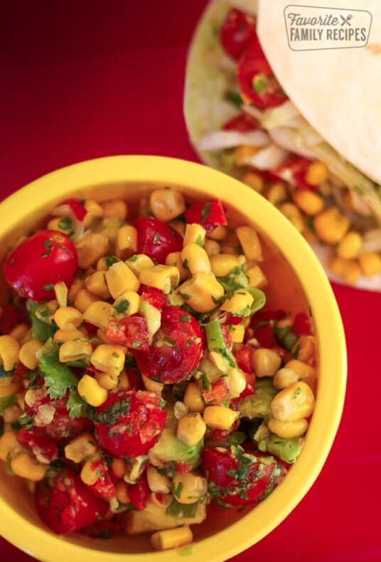 Fresh Corn Salsa in a yellow bowl with tortillas in the background.