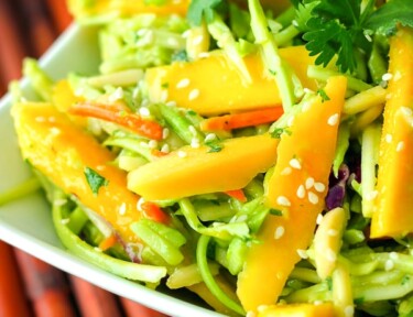 Fresh Mango Avocado Coleslaw topped with a garnish in a white bowl.