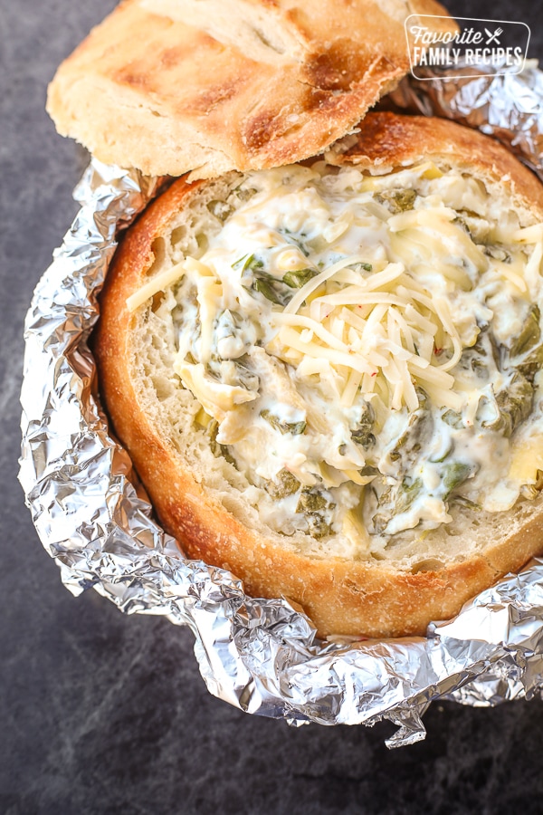 spinach artichoke dip in a bread bowl with foil covering